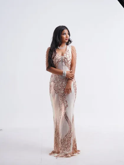 An elegant full-length shot of a white and rose gold sequin gown with delicate shoulder chains, perfect for a glamorous "carnival style" look.