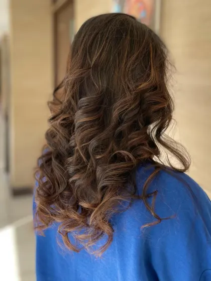 A different perspective of the soft, curled style, showing how the curls fall naturally and create a sense of movement.