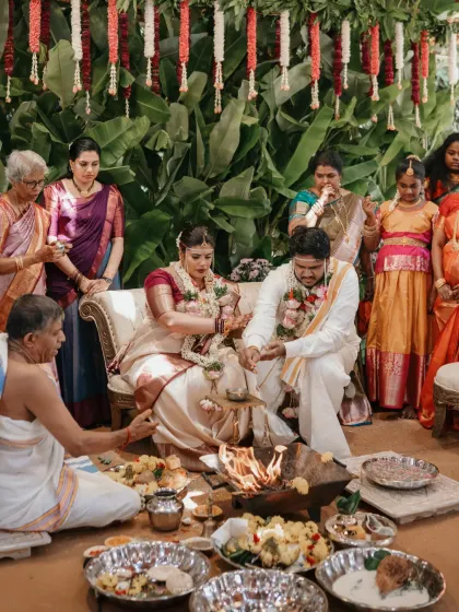 The couple participates in the havan, the sacred fire ceremony, surrounded by their family in a traditional setting.