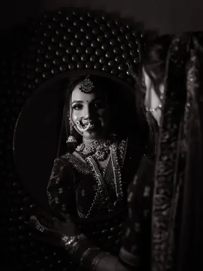 A dramatic black and white photo of the bride looking at her reflection, a moment of quiet contemplation on her big day.
