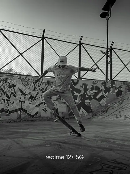 A black and white shot of a skateboarder mid air at a skatepark. The monochrome edit emphasizes the form and action, while the graffiti background adds an urban edge.
