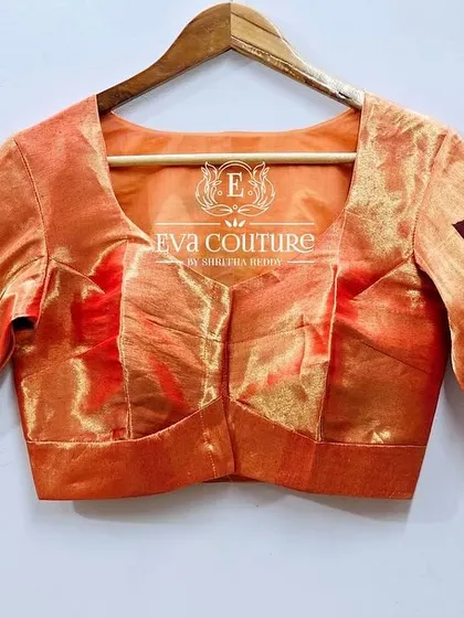 The front view of the peach-colored Paithani silk blouse. The simple front allows the intricate work on the sleeves and back to stand out.