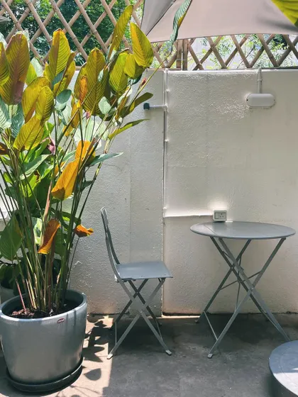 A quiet corner in our garden, waiting for you. This simple setup is perfect for a solo coffee or a one-on-one chat.