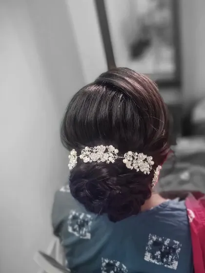 A classic and elegant bridal bun. This intricate updo is decorated with a beautiful crystal hair accessory, perfect for a reception or engagement party.