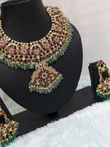 The full Jadau neckpiece with a large pendant and matching Chaandbaali earrings. This is perfect for a traditional lehenga.