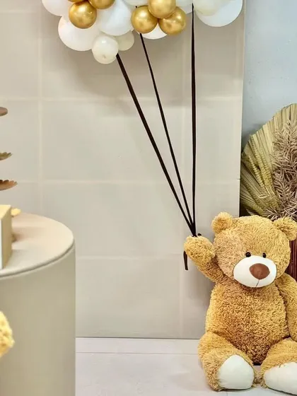 A teddy bear holding a balloon bouquet, a simple and sweet detail for any baby shower or first birthday.