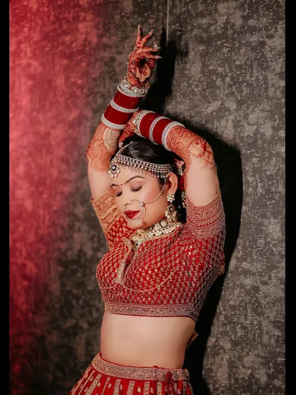 A dramatic and artistic shot of me on my wedding day, captured in a "lal ishq" theme. The red lehenga, the pose, and the lighting all come together beautifully.