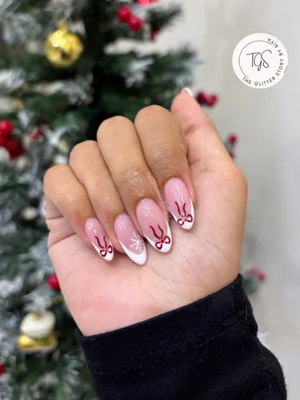 Another look at the delicate Christmas French manicure, showing the hand-painted red bows and snowflake against the clean white tip.