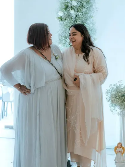 Two generations sharing a laugh in their custom pastel outfits. The flowing georgette gown and the elegant salwar suit were designed to complement each other beautifully.