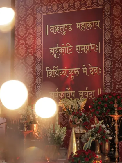 A sacred Hindu mantra is elegantly displayed on a textured red backdrop, surrounded by floral arrangements. This detail shows my commitment to incorporating personal and spiritual elements into the decor.