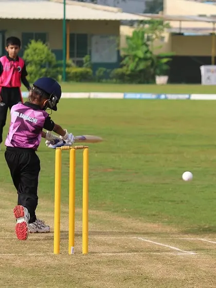 A U-10 batter connects with the ball, showcasing developing batting skills.