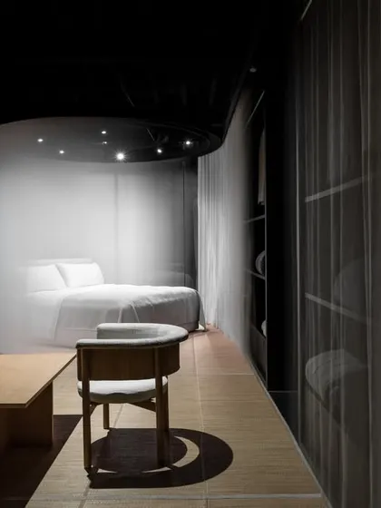 The retail space is designed as a series of interconnected zones. Here, a quiet discussion area is positioned to overlook the veiled product pods, creating a layered experience where clients can consult and reflect within the immersive Japandi-inspired interior.