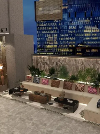 A multi-level seating area with built-in planters and colorful cushions is set against a backdrop of large, handcrafted stone relief panels.