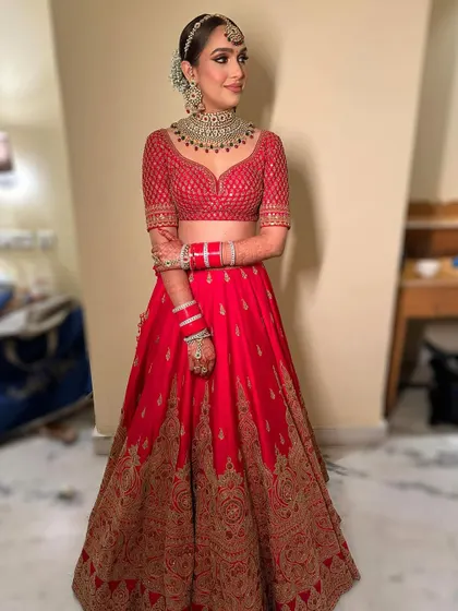 The complete look, showing how the modern makeup with bronze eyes perfectly complements the classic red lehenga and traditional jewelry.