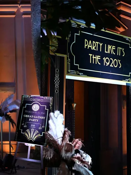 Welcome to the party. A custom welcome sign and art deco-style feather arrangements greeted guests, immediately immersing them in the Great Gatsby theme.