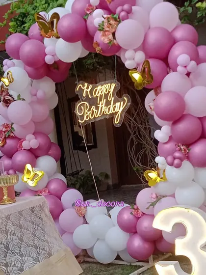 A closer look at the outdoor butterfly theme, showing the intricate details of the pink and white balloon ring and the elegant cake table setup.