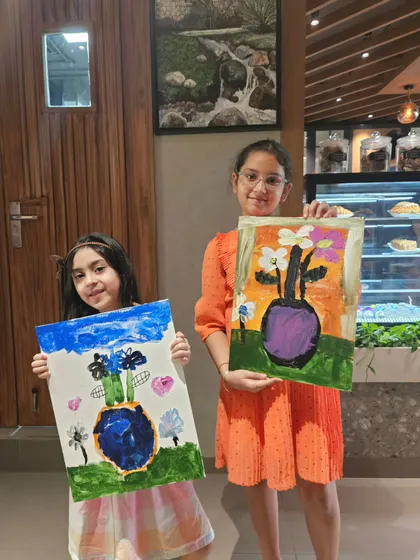Two young sisters proudly displaying their finished floral vase paintings. It’s so rewarding to see kids explore their creativity and leave with art they are proud of.