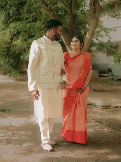 A full-length portrait of the couple walking together outdoors, showcasing their elegant, coordinated outfits.