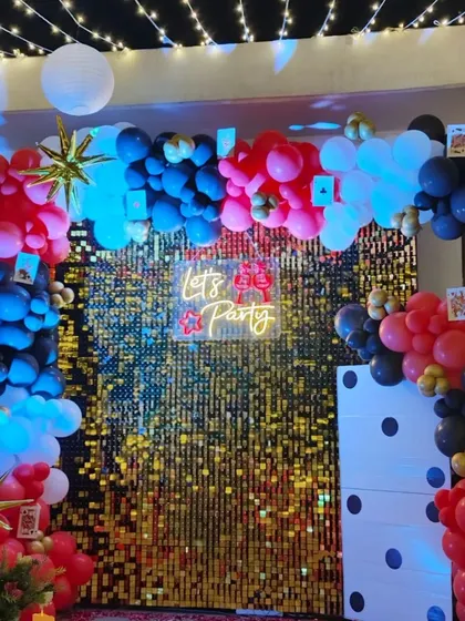 A close-up of a casino-themed Diwali photo booth, featuring a balloon arch with playing card details and a shiny gold backdrop.
