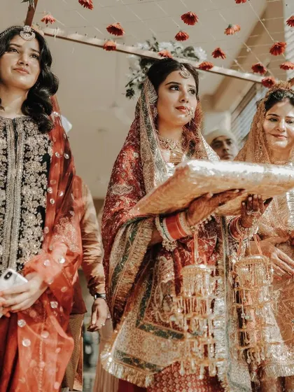 The bride's solemn and graceful entrance during a traditional Punjabi wedding ceremony, surrounded by her family.