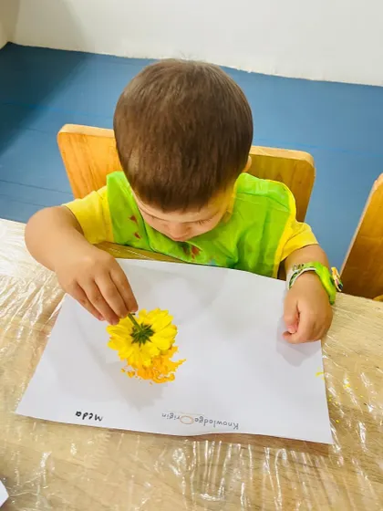 This toddler is learning about cause and effect as he presses the flower onto the paper and sees the color transfer. It's a simple yet powerful lesson in process art.
