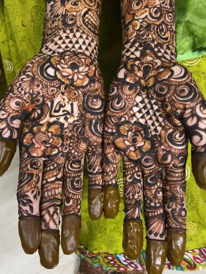 This bride's name, 'Fathima', is written in Arabic script on her palm, surrounded by a beautiful floral design.
