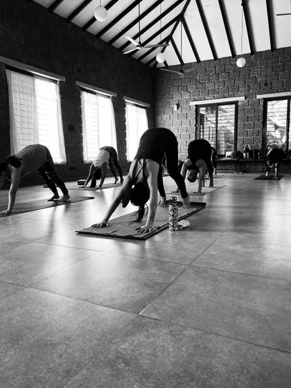 Students moving through a vinyasa, transitioning into Adho Mukha Svanasana. The black and white format highlights the forms and lines of the body in motion.