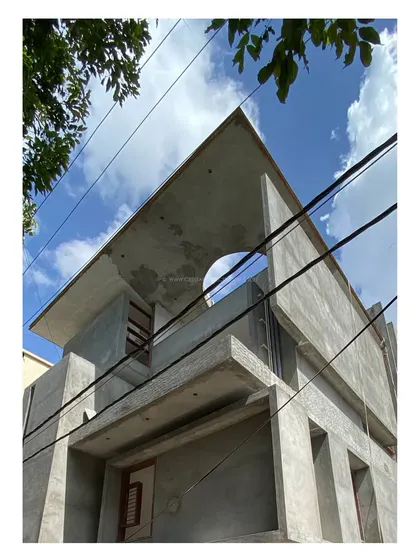 'Residence 96' in its raw concrete form. This worm's-eye view emphasizes the building's angular roofline and circular oculus, key features of the design.