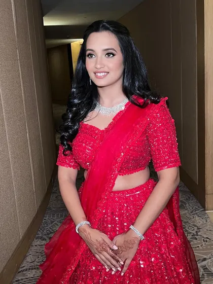 Shining bright in a classic red lehenga. The makeup is kept glowing and radiant to complement the bold outfit, ensuring the whole look is balanced and beautiful.