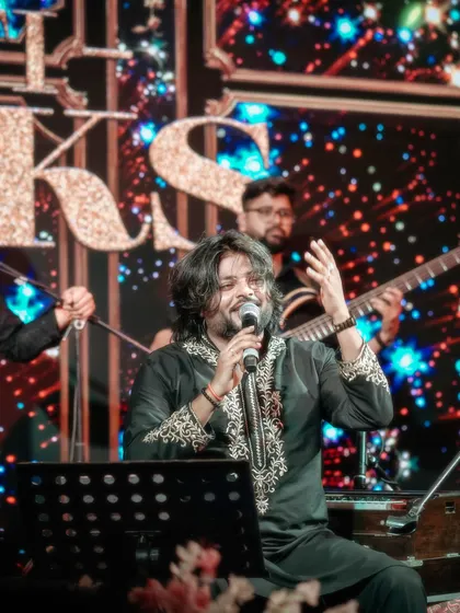 A powerful shot of me singing with passion, with the band and our signature stage backdrop creating a professional and visually appealing setting.