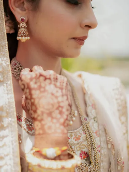 A soft-focus shot highlighting the bride's delicate features and the intricate pattern of her mehndi.