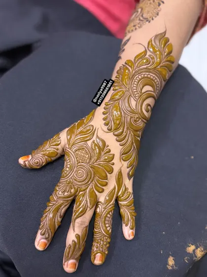 This design features bold, flowing leaves and spirals that cover the entire back of the hand. It's a classic Arabic henna style that is always in demand.