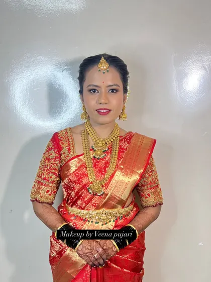 A beautiful bride in a classic red Kanjivaram saree. The look is completed with traditional gold jewelry, a neat updo, and makeup that highlights her features.