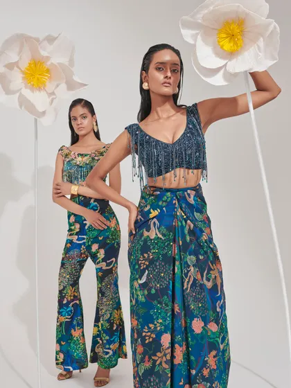 Coordinated separates in a vibrant blue floral print. The fringed blouse and draped skirt offer a playful yet chic option for a destination wedding.