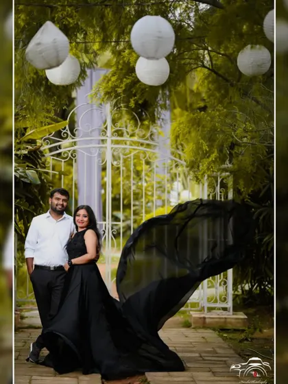 A classic pre-wedding portrait in a garden. The couple looks timeless in a black flying gown and a white shirt.