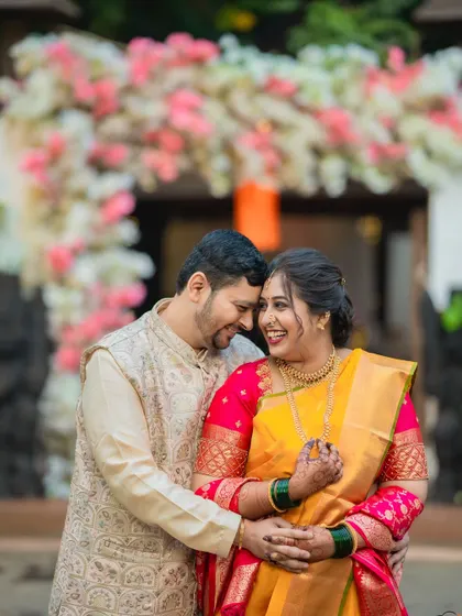 A happy, candid moment of a Maharashtrian couple sharing a laugh in front of their wedding decor.