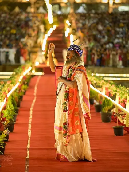 I am waving to the devotees as I walk the ceremonial path during Maha Shivratri. The joy and love from the crowd are overwhelming and make the celebration truly special.