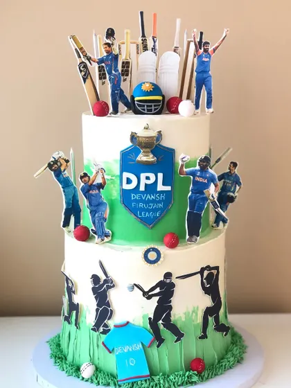 A grand two-tiered cake for a true cricket fan, decorated with player cutouts, bats, balls, and a custom league logo.