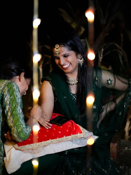 A candid, joyful moment during a mehendi session, captured through a string of fairy lights. The bride's laughter is the best part of my job.
