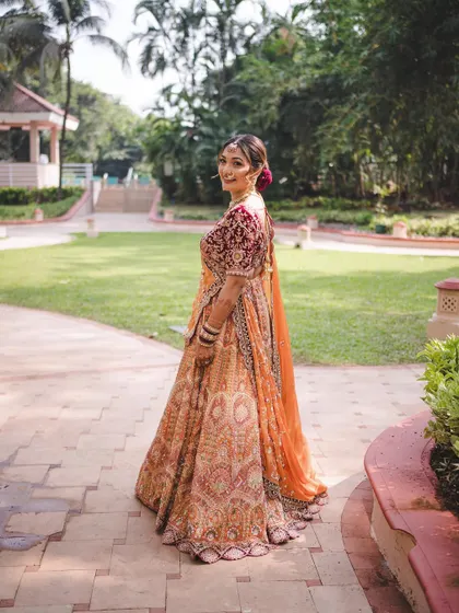 A back view of the bride, showing off her beautiful lehenga and the elegant hairstyle. This look is all about grace from every angle.