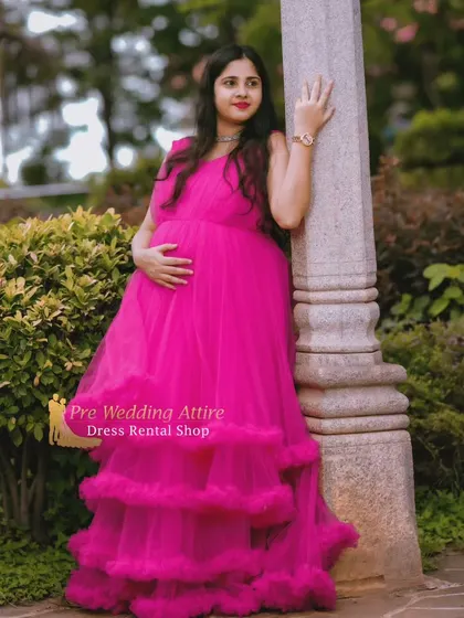A classic pose against a pillar, highlighting the silhouette of the dark pink ruffled gown. The full skirt pools beautifully at the bottom, adding a touch of grandeur to the portrait.