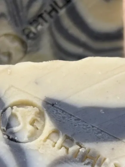 A close-up of the intricate swirl design and our brand stamp on the Charcoal & Dead Sea Mud Soap. Each bar is a unique piece of art.