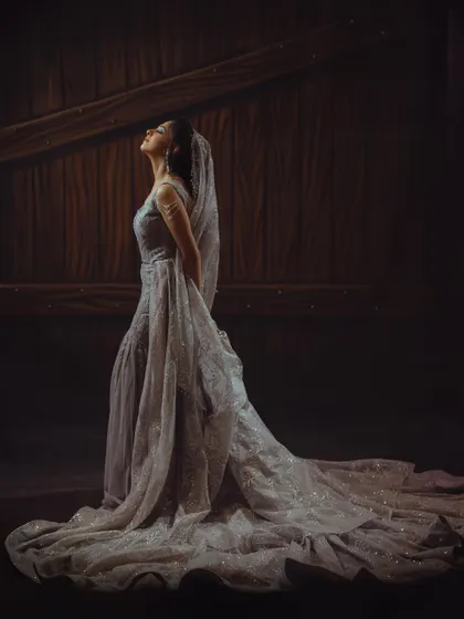 A dramatic and elegant portrait of the bride, her magnificent gown spread out, creating a powerful and artistic image.