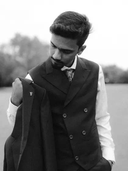 A classic black and white portrait of the groom, Aman. His sharp suit and thoughtful expression create a timeless and sophisticated look.