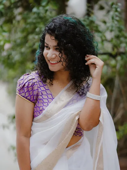 A beautiful portrait celebrating Onam. Her bright smile and the way she touches her unique curly hair add so much personality to the traditional look.