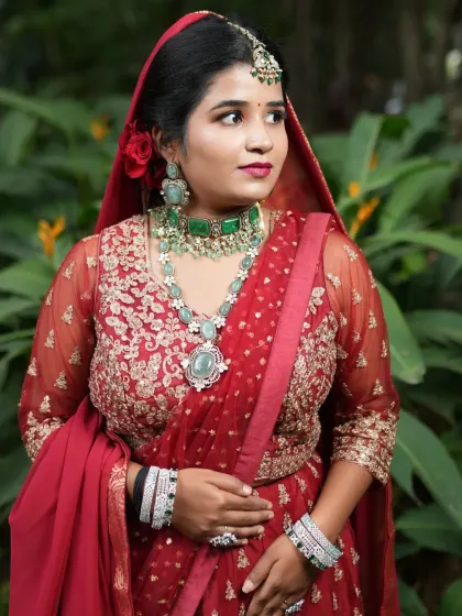 A close-up portrait of the bride, highlighting the beautiful green choker, maang tikka, and earrings. This look is perfect for a bride who wants to feel like a movie star.