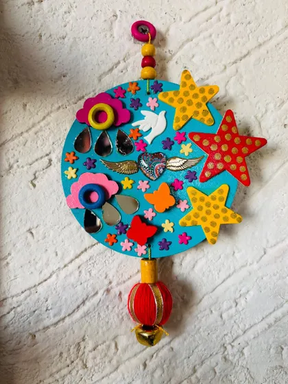 The 'Our Angels' hanging against a textured wall. The bright turquoise base makes all the colorful, symbolic elements pop.