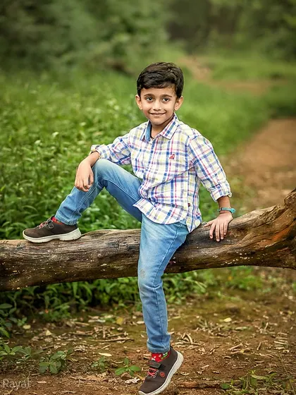 A confident young boy poses on a fallen log in the forest. I love empowering kids to show their personalities during our shoots.