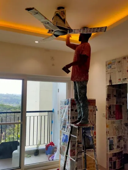 Even the smallest details get our full attention. This painter is on a ladder, carefully painting around a ceiling fan that has been wrapped in newspaper for protection.