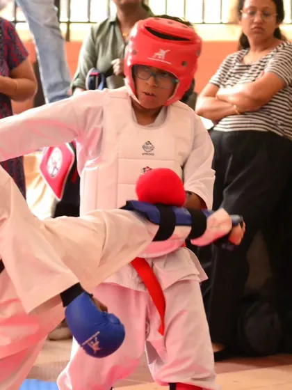 A young karateka in full protective gear prepares to block an opponent's move. These moments in a tournament are where training, discipline, and quick thinking come together.
